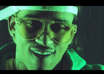 Primer plano de artista urbano con gafas, gorra al revés y luz verde, ideal para bryant myers