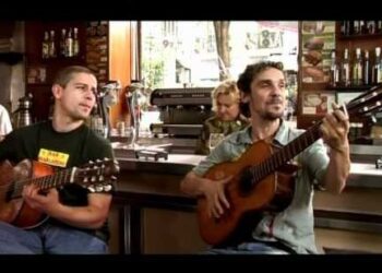 Dos músicos tocando guitarras en un bar con ambiente íntimo; Caché de Estopa: Descubre cuánto cobran por sus conciertos
