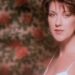 Retrato íntimo de una cantante en primer plano frente a un papel tapiz floral, Dónde vive la cantante: descubre su hogar y estilo de vida.