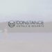 Descubre por qué Constance Prince Maurice es el hotel más deseado de la deliciosa Mauricio: logotipo de Constance Hotels & Resorts sobre una playa tranquila con una persona caminando junto al agua.