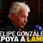 Hombre mayor en perfil frente a micrófonos y cámaras en una rueda de prensa, imagen que ilustra dónde trabaja este político y sus proyectos recientes.