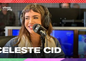 Mujer sonriente con auriculares en un estudio de radio frente a un micrófono