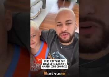 Padre con barba abrazando a niño rubio con venda sobre la ceja y ojo morado en una sala