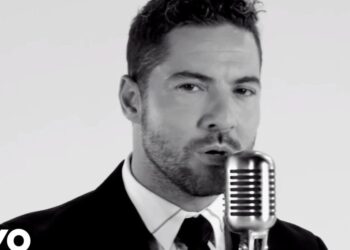 Cantante masculino en blanco y negro frente a un micrófono retro, retrato íntimo de un artista no identificado