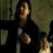 Cantante de melena larga cantando en ambiente íntimo, gesto apasionado