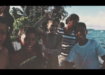 Niños jugando en la orilla del mar con palmeras y barcos, inspiración para dj nano