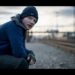 ¿De dónde es Ed Sheeran? Descubre sus raíces y su historia 35 Hombre pelirrojo con gorro y chaqueta sentado junto a las vías del tren al atardecer