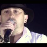 Cantante con sombrero y micrófono en primer plano, Caché de El Barrio: Descubre cuánto cuesta contratarlo hoy