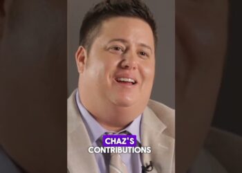 Retrato de una persona sonriente durante una entrevista en estudio, con texto en pantalla que hace referencia a contribuciones personales.