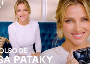 Mujer sonriente en primer plano sosteniendo un estuche de maquillaje junto a un bolso sobre un sofá azul