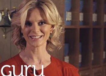 Mujer rubia sonriente con blusa roja frente a estanterías y un logotipo en la esquina inferior izquierda