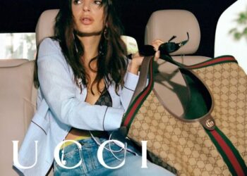 Mujer en el asiento trasero con blazer azul, top de encaje y gran bolso Gucci monograma
