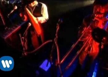 Concierto íntimo en escenario con músicos, luces rojas y azules y micrófonos: ¿De dónde es Bunbury? Descubre sus raíces y su historia musical