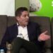 Hombre sentado en un sofá con traje y micrófono en una entrevista, La esposa de Ernesto Laguardia: descubre su historia y secretos