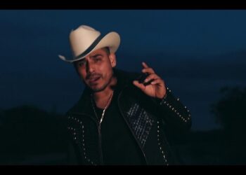 Hombre con sombrero vaquero blanco y chaqueta negra cantando al anochecer — La familia de Espinoza Paz: secretos y momentos inolvidables