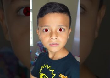 Niño con ojos rojos editados y camiseta negra con diseño amarillo, mirada sorprendida; Descubre los 10 nombres de bebé para otoño que deslumbrarán, ¡incluyendo uno que significa ‘princesa dorada’!