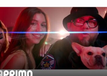 Grupo festivo en un ambiente nocturno con un hombre con gorro y gafas sosteniendo un bulldog francés; Descubre dónde vive David Beckham y su lujosa mansión en Inglaterra