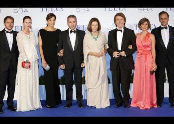 Ocho adultos en gala posan sobre una alfombra azul en un evento, imagen relacionada con La familia de Raphael: secretos y curiosidades de su vida familiar.