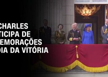 Descubre lo que realmente se dijo sobre la paternidad, ¡te sorprenderá! Miembros de la realeza en un balcón oficial con estandarte rojo y borlas doradas durante una conmemoración.