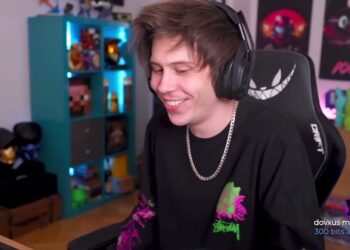 Persona joven sonriendo con auriculares en un estudio de streaming, silla gamer y estantería iluminada.