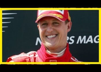 Piloto de carreras sonriente con mono y gorra rojos en un podio