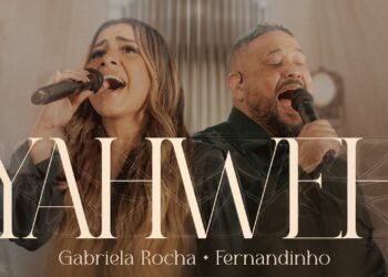 Dúo vocal en estudio cantando con intensidad frente a micrófonos bajo luces cálidas.