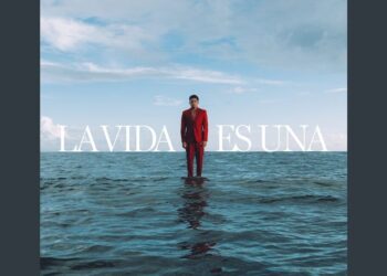 Hombre de pie en el mar con traje rojo frente a un cielo amplio, ¿Cuánto dinero tiene Arcángel? Descubre su impresionante fortuna