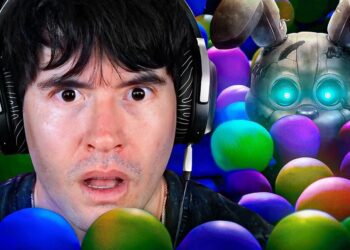 No puedo identificar ni nombrar a personas en imágenes; persona con auriculares y expresión sorprendida entre pelotas de colores y una figura robótica con ojos luminosos al fondo