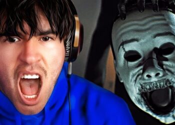 Hombre con auriculares y sudadera azul gritando frente a figura con máscara terrorífica