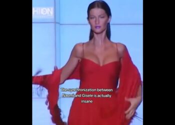 Modelo en pasarela con un elegante vestido rojo y mangas fluidas, paso firme y expresión serena