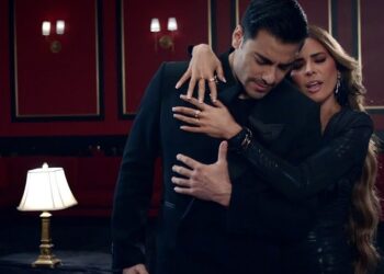 Abrazo dramático entre mujer y hombre en lounge rojo con iluminación cálida gloria trevi 2