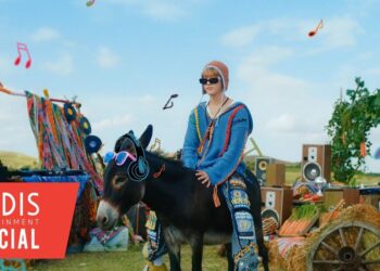 Persona joven con suéter colorido montada en un burro adornado con gafas de sol y notas musicales en un ambiente festival al aire libre; Hijos de Kratos: descubre la historia y legado de Atreus y Calíope