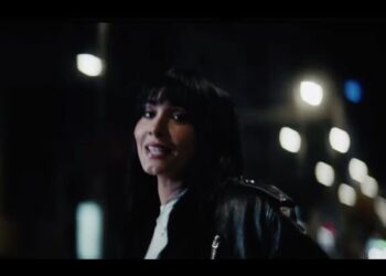 Persona con chaqueta de cuero y flequillo sonriendo en una calle nocturna con luces desenfocadas — Descubre por qué Madrid se ha convertido en el imán de influencers de todo el mundo y lo que nadie te ha contado