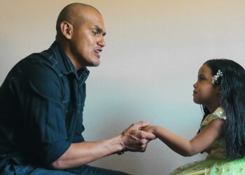 Hombre adulto sosteniendo las manos de una niña pequeña en una conversación afectuosa; Cuántos hijos tuvo Gandhi: descubre la historia familiar del líder