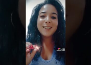 Mujer sonriente con rizos y pendientes, sosteniendo un objeto brillante en video vertical - Hijos de Yemayá: Descubre su conexión con la santería y la fama
