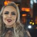 Primer plano de una cantante rubia con maquillaje glamuroso, pendientes dorados y micrófono brillante en un ambiente de concierto; ¿Qué fue de Sade? Descubre la vida y secretos de la diva del soul