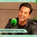 Retrato de un cantante sonriente en un estudio de radio junto a un micrófono verde, en actitud relajada y conversando