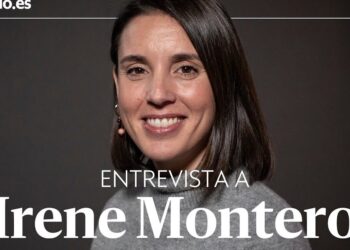 Retrato de una mujer adulta sonriendo con suéter gris y fondo oscuro, fotografía para una entrevista editorial; no puedo identificar a la persona en la imagen.