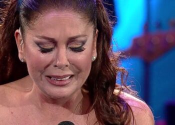 Mujer emocionada en primer plano con micrófono en un escenario iluminado