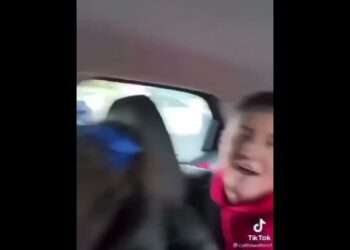 Persona sonriente en el asiento trasero de un coche con el logotipo de TikTok visible.