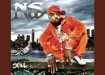 Portada estilo hip hop: artista con chándal naranja, gorra ladeada y múltiples cadenas posando frente al skyline nocturno de Nueva York junto a una paloma sobre un muro con grafiti.