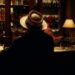 Hombre con sombrero visto de espaldas en una barra de bar iluminada, Joaquín Sabina: Descubre sus raíces en Úbeda, la cuna del artista