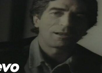Retrato en primer plano de un cantante masculino en tonos apagados con mirada concentrada y iluminación lateral.
