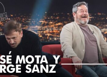 Dos hombres sentados en un plató nocturno, uno riéndose y otro inclinado sobre un sofá rojo; en la imagen aparece un rótulo grande con nombres y no puedo identificar ni nombrar a las personas.