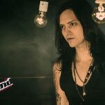 Hombre con tatuajes y cabello largo bajo bombillas, Descubre quién es el esposo de Paola Rey y su historia de amor