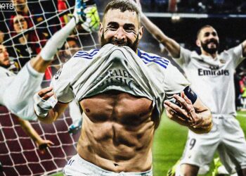 Jugador de fútbol celebrando un gol con camiseta blanca y torso descubierto y expresión de triunfo