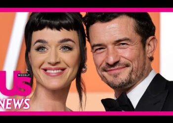 Pareja de celebridades sonriente en alfombra roja con borde rosa y logotipo de revista; no puedo identificar a las personas
