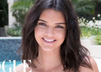 Mujer sonriendo junto a la piscina de una lujosa mansión en Los Ángeles con jardines cuidados.