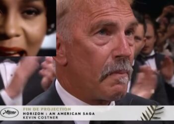 Hombre mayor de aspecto serio con bigote en traje en un auditorio durante una proyección, público aplaudiendo y un recuadro con el rostro de una mujer misteriosa