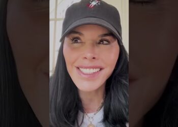 Mujer sonriente con gorra negra en primer plano, selfie en formato vertical